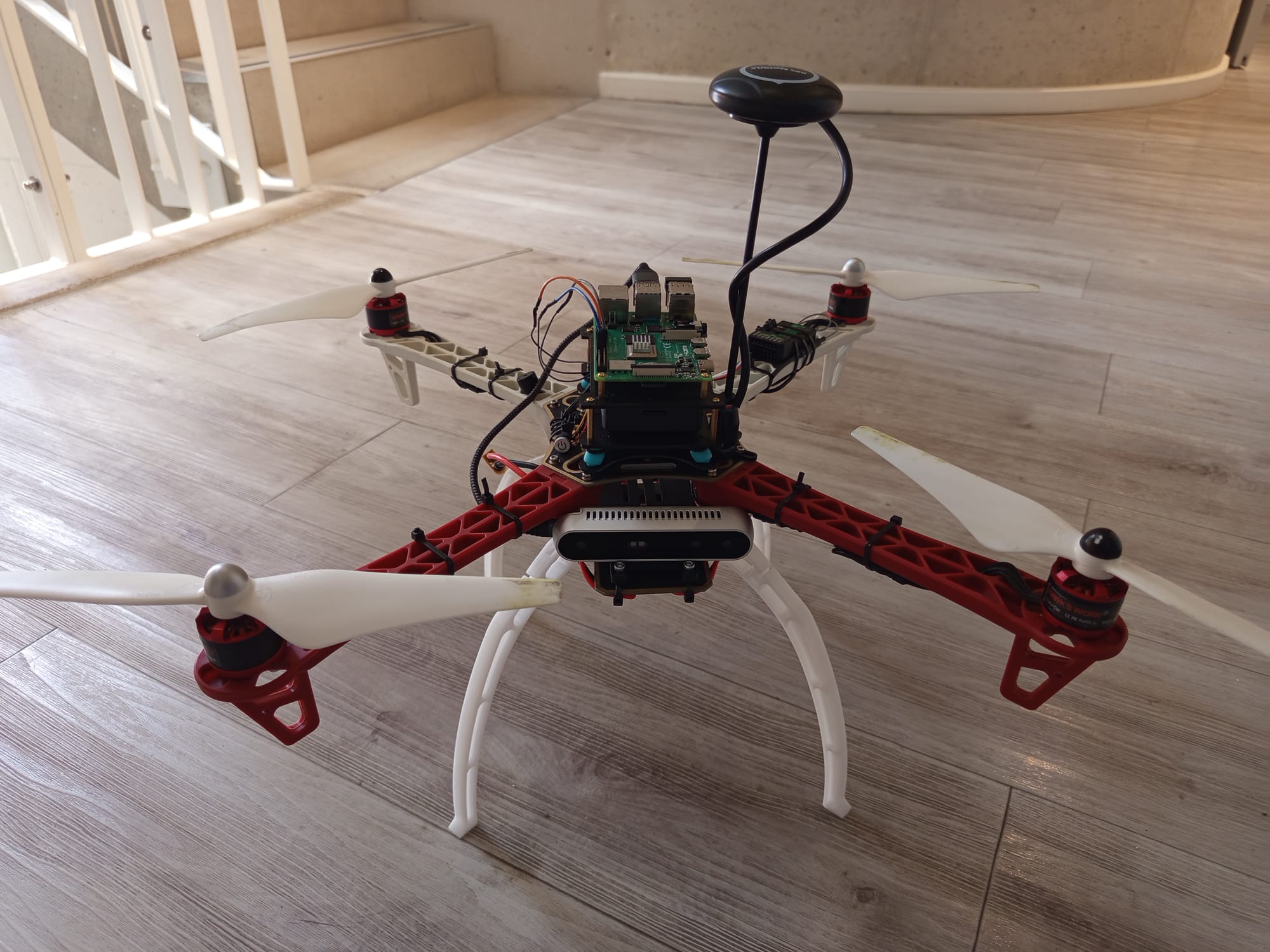 The assembled F450 quadcopter on the floor, with Pixhawk, Raspberry Pi 4B, and GPS mounted on the airframe.